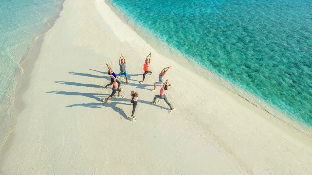 Guest practicing yoga on the quiet sandbank near Fodhdhoo, Maldives.