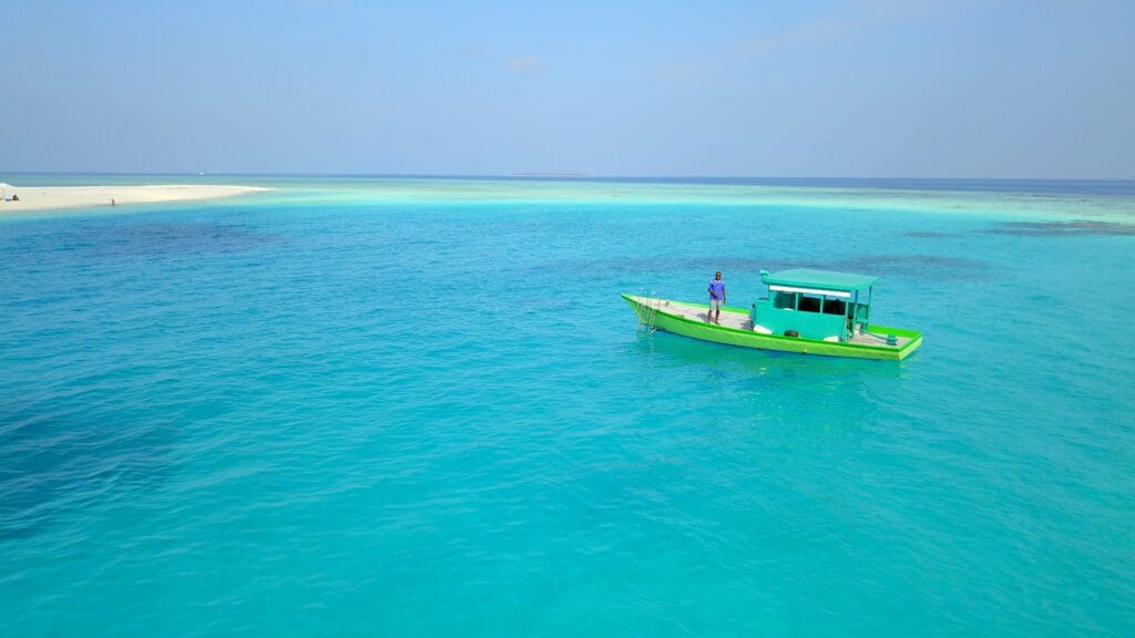 A traditional Maldivian fishing boat anchored near the sandbank of Fodhdhoo Island.