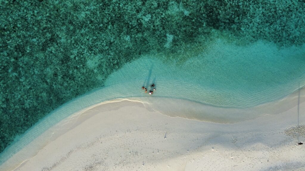 Aerial view of a secluded sandbank with guests enjoying the beach, the ideal getaway.