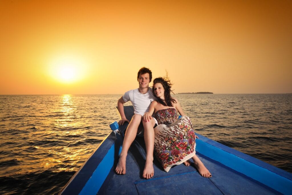 Couple enjoying a romantic sunset cruise, a highlight of their stay at a guest house in Maldives.