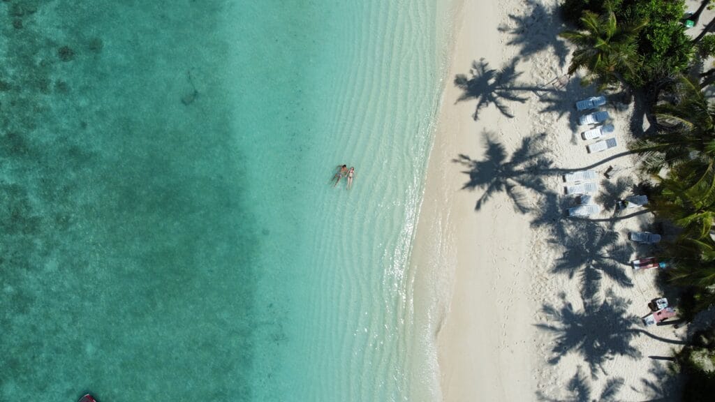 Aerial picture of a couple at the reef area of Fodhdhoo, showing the bikini beach during their romantic getaway Maldives guesthouse stay.