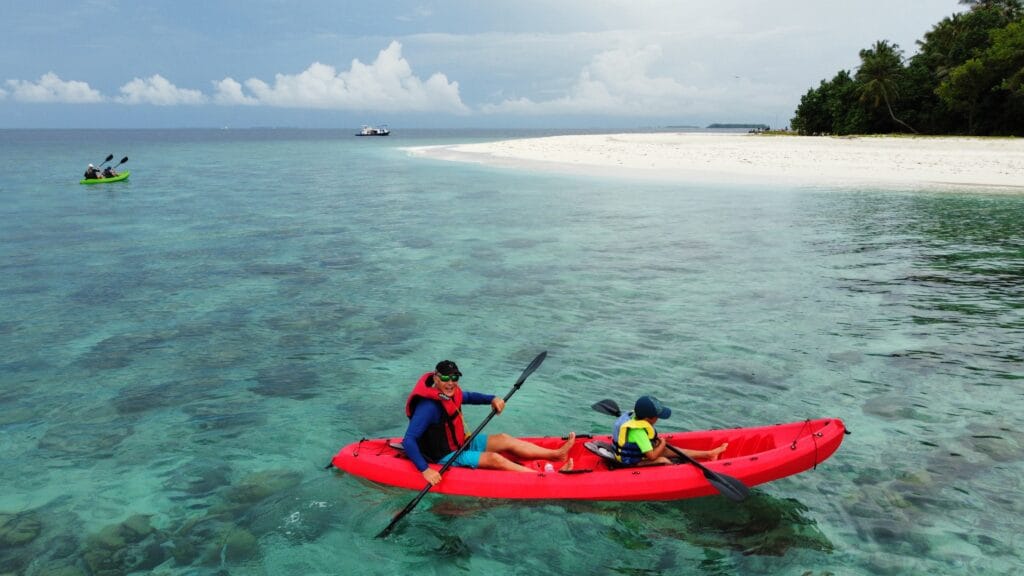 2 guests riding a canoe at the Fodhdhoo reef, enjoying the best guest house experience in the Maldives