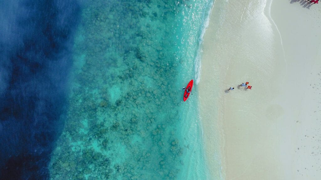 Aerial picture of the sandbank near Fodhdhoo Island, with guests arriving on a canoe to Discover Maldives sandbank.