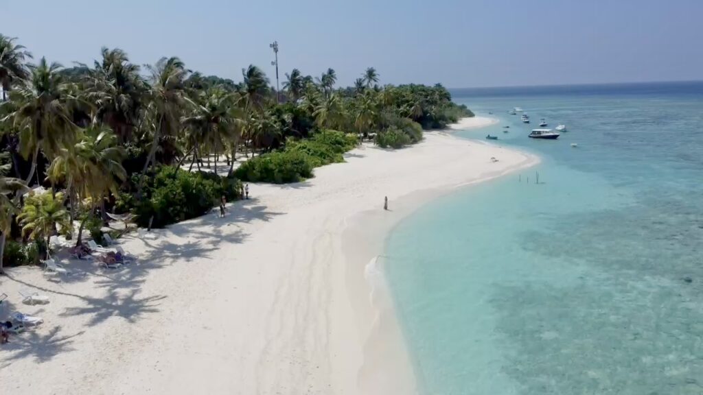 A drone picture of a guest walking on Fodhdhoo bikini beach during the best guest house experience in the Maldives