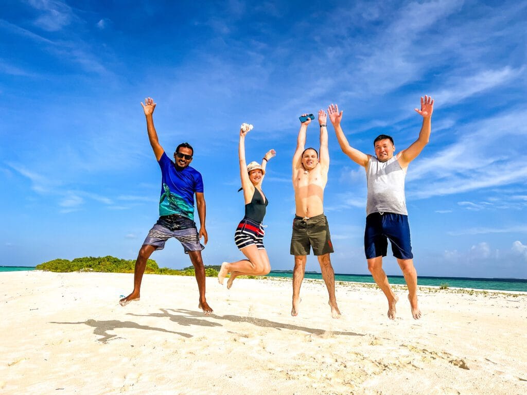 4 guests enjoying Fodhdhoo beach, having the best guest house experience in the Maldives