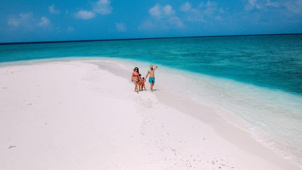 A family of 4 guests walking at the sandbank of Fodhdhoo Island