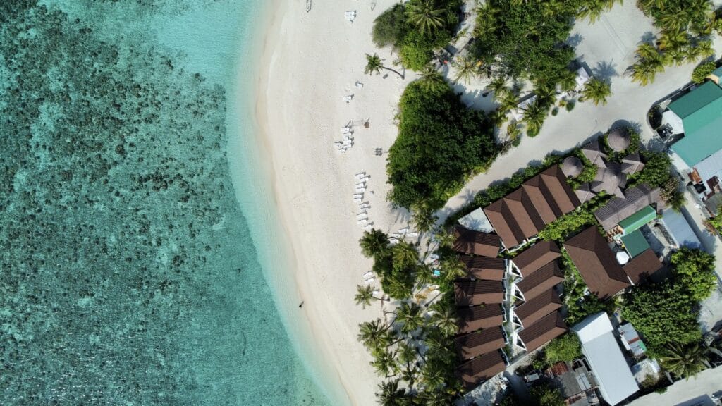 Aerial view of Fodhdhoo Island showcasing sea view villas of our guesthouse and the bikini beach area to Discover Maldives.