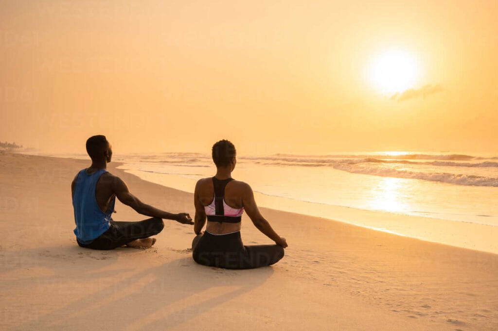 Two couples enjoying the sunset while sitting on the beach, adding warmth to their romantic getaway.