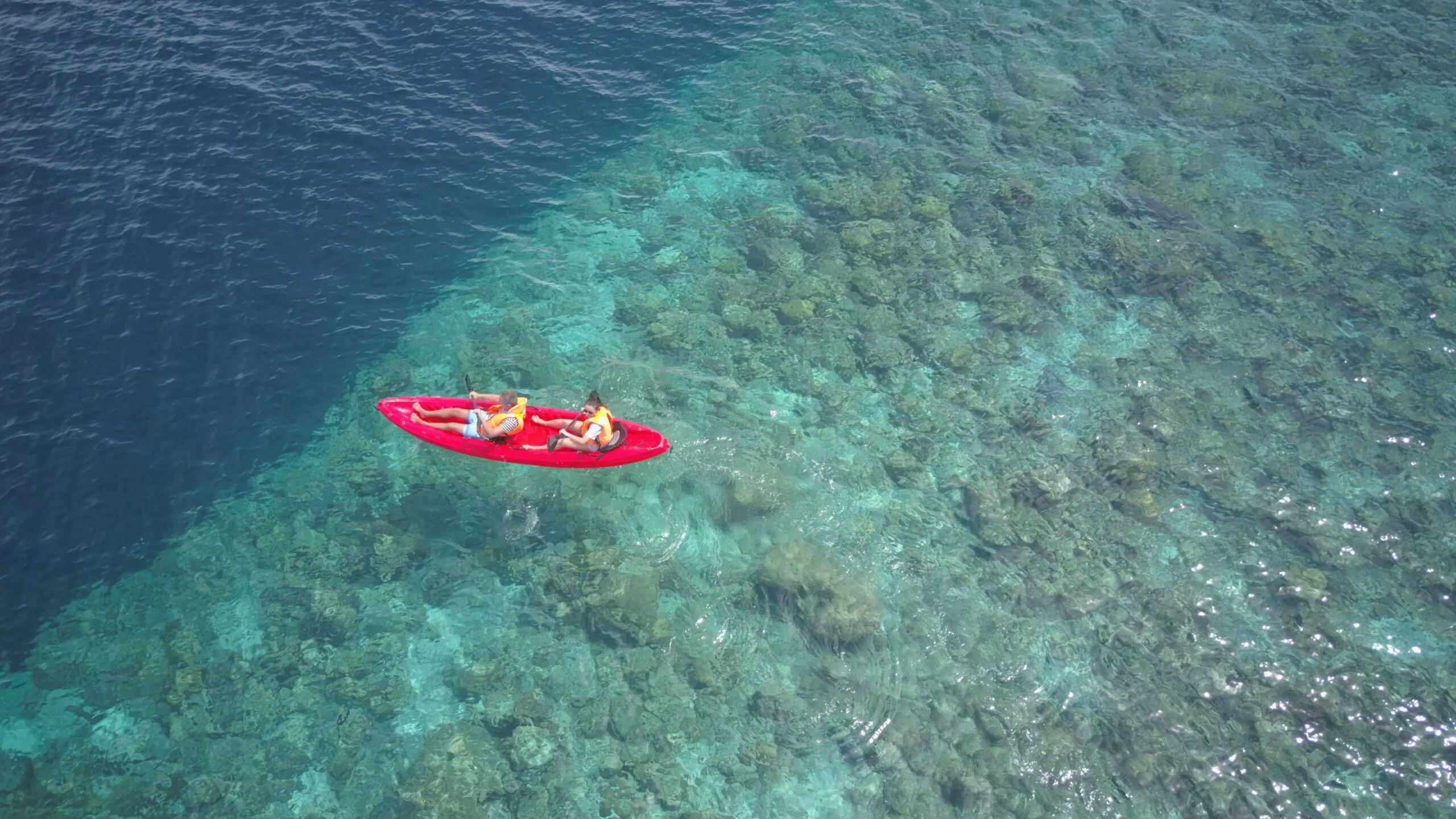 Duo paddling side-by-side in a clear kayak off Fodhdhoo, enjoying an Adventurous Holiday at Maldives