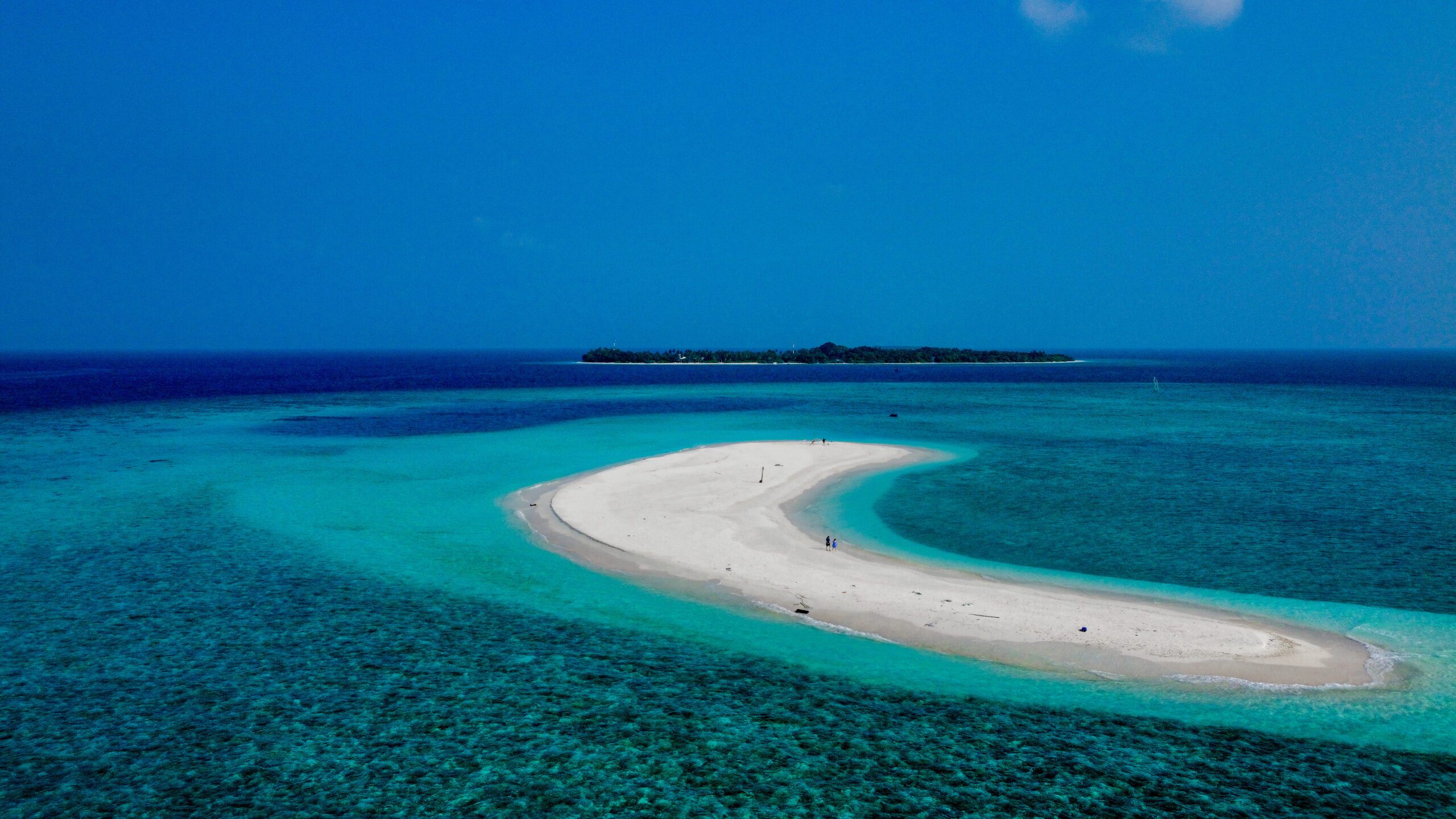 Distant drone shot of a serene sandbank, showcasing a peaceful Holiday at Maldives escape