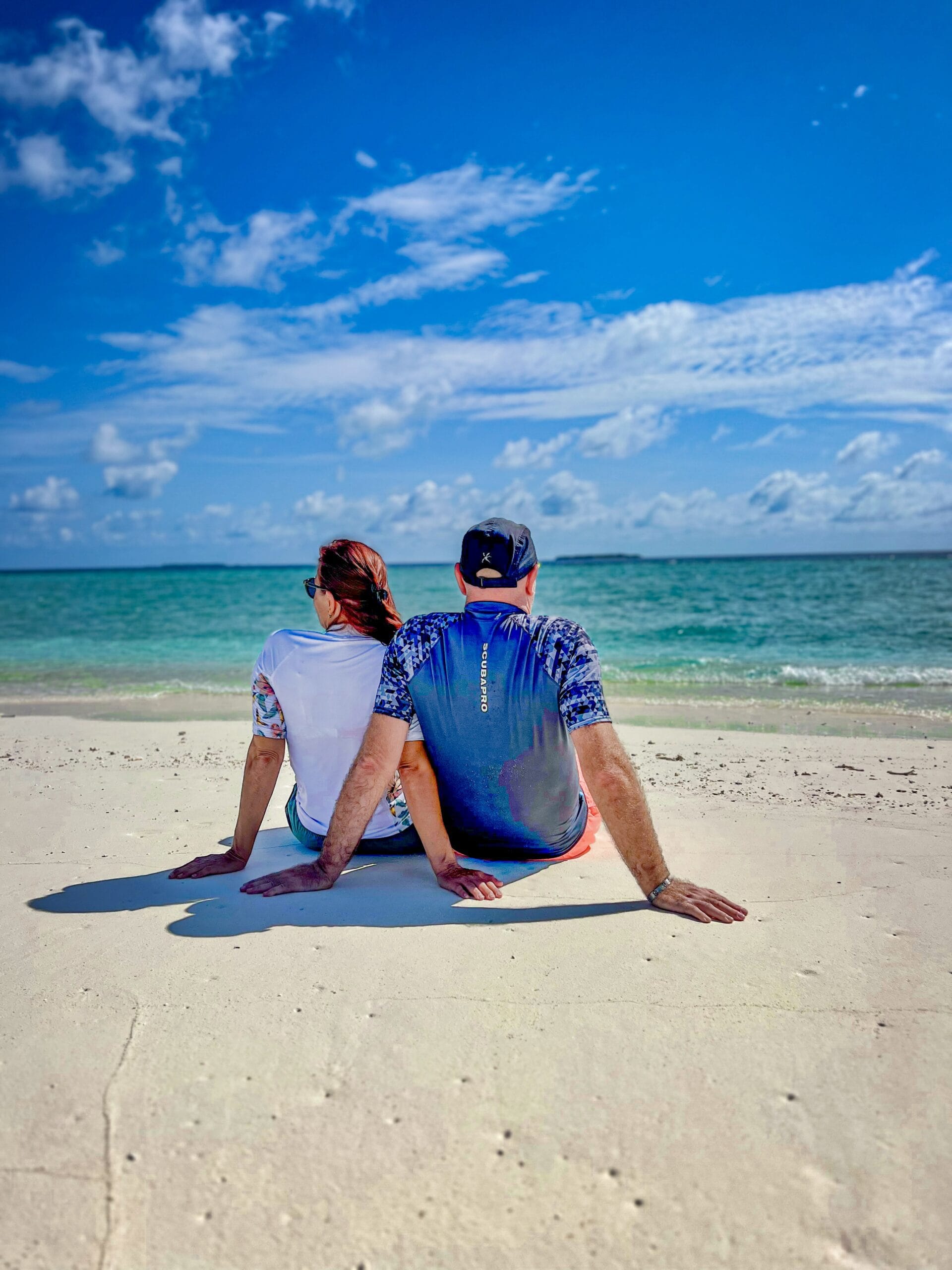 Two beach lovers admiring rolling waves, enhancing their Holiday To The Maldives with ocean serenity”