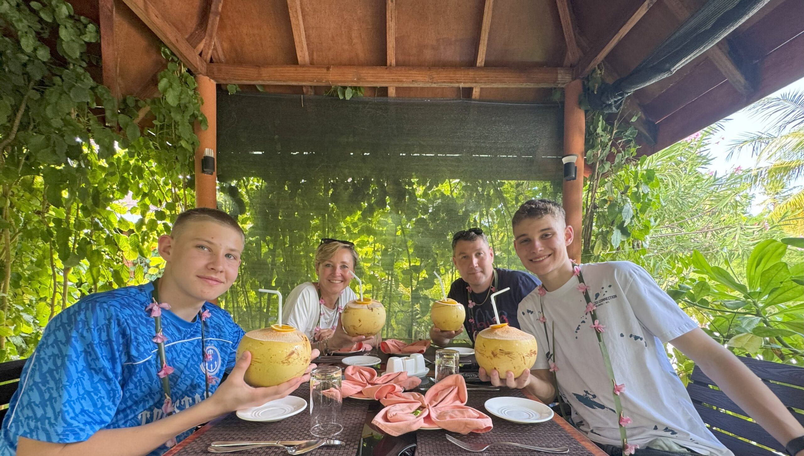 Smiling parents and kids sipping fresh coconut drinks at Lobster Grill during a Maldives For Families lunch.