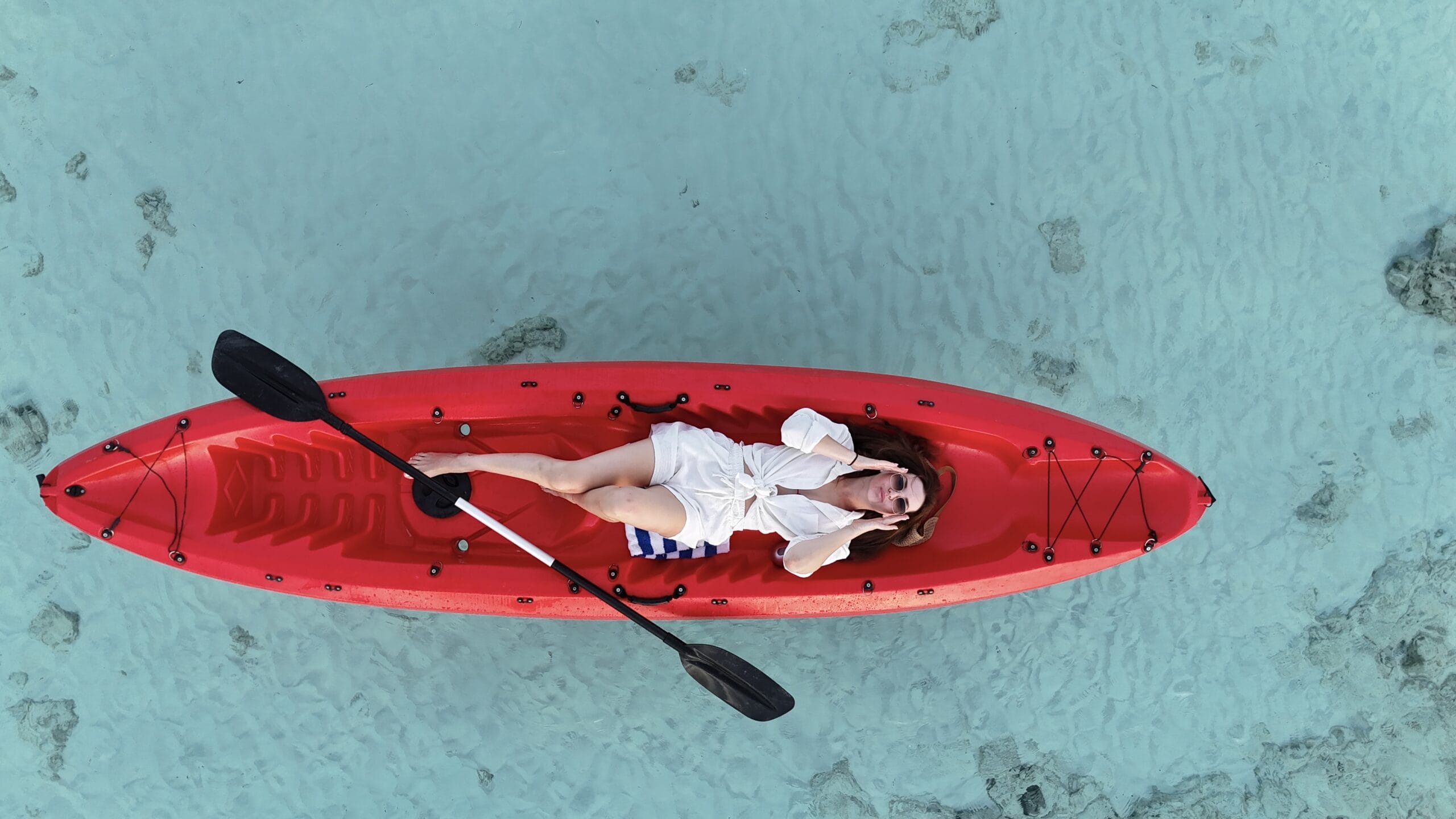 Relaxed solo kayaker lying back on turquoise water, savoring her Maldives For Solo Travelers moment