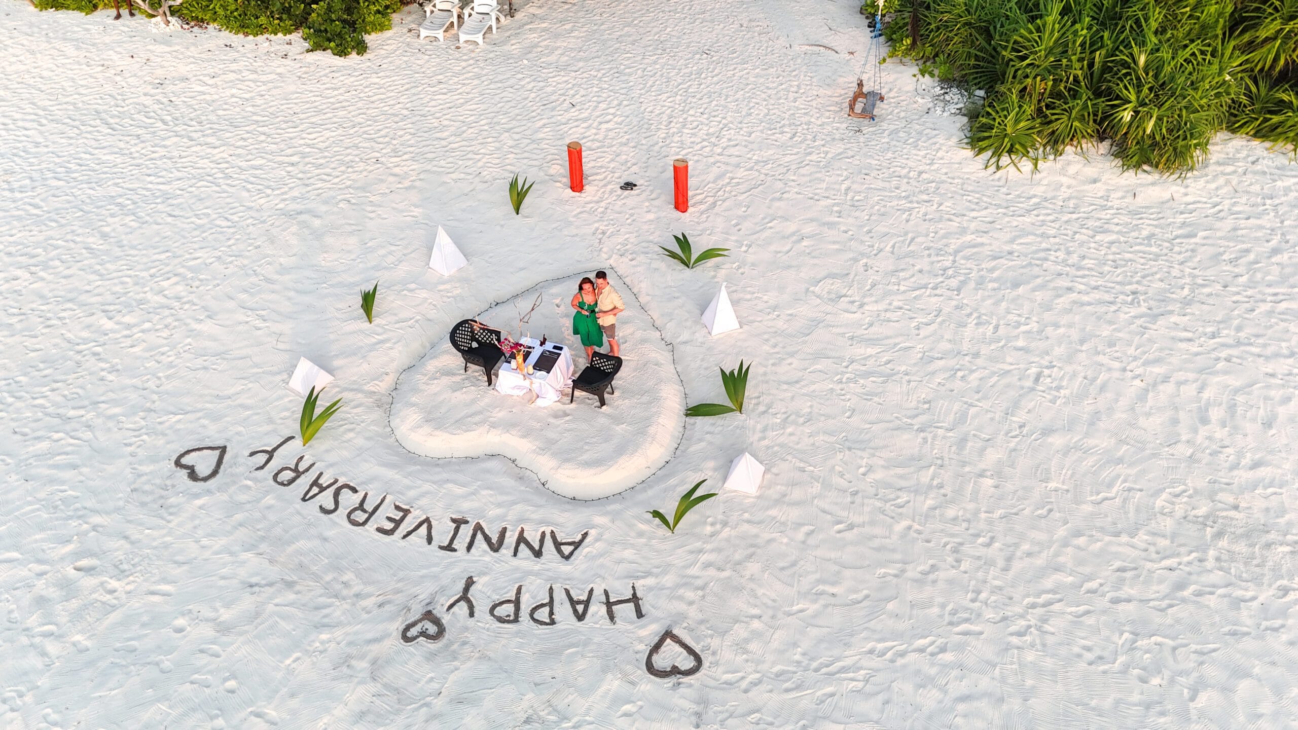 Romantic couple captured by drone walking hand-in-hand along quiet Fodhdhoo shoreline
