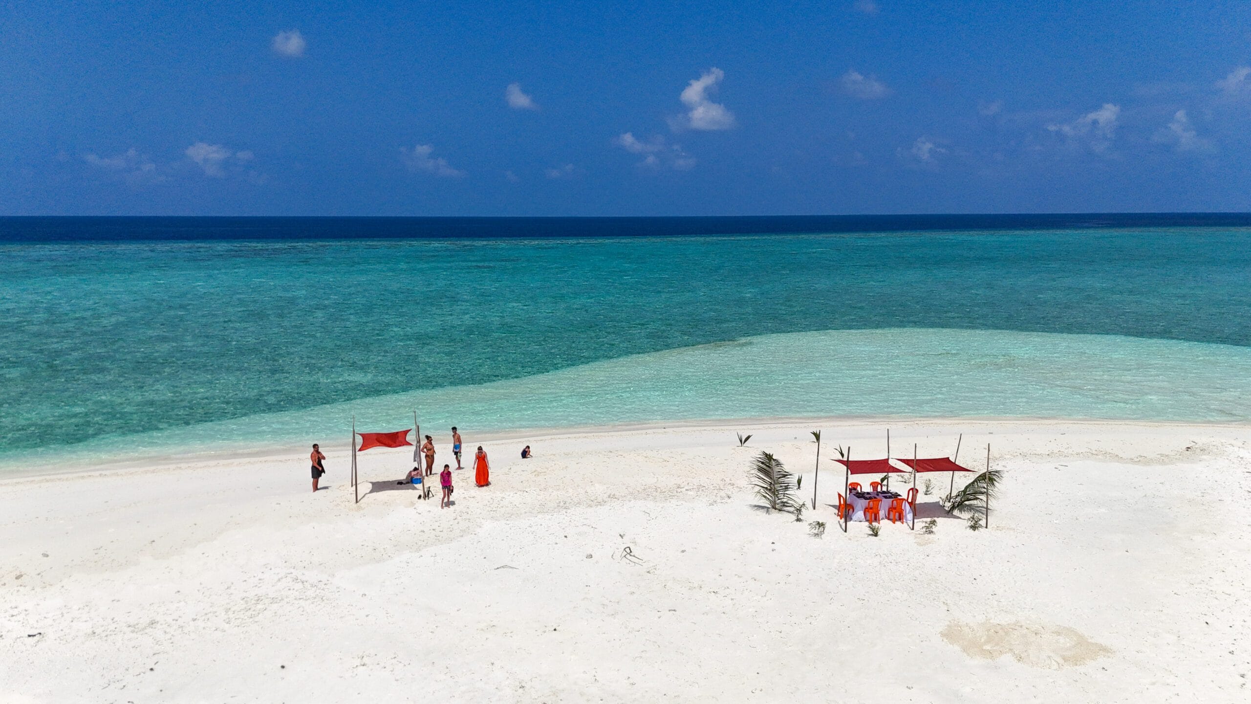 High-angle shot of excited guests picnicking on a sandbank, highlight of an Adventurous Holiday at Maldives