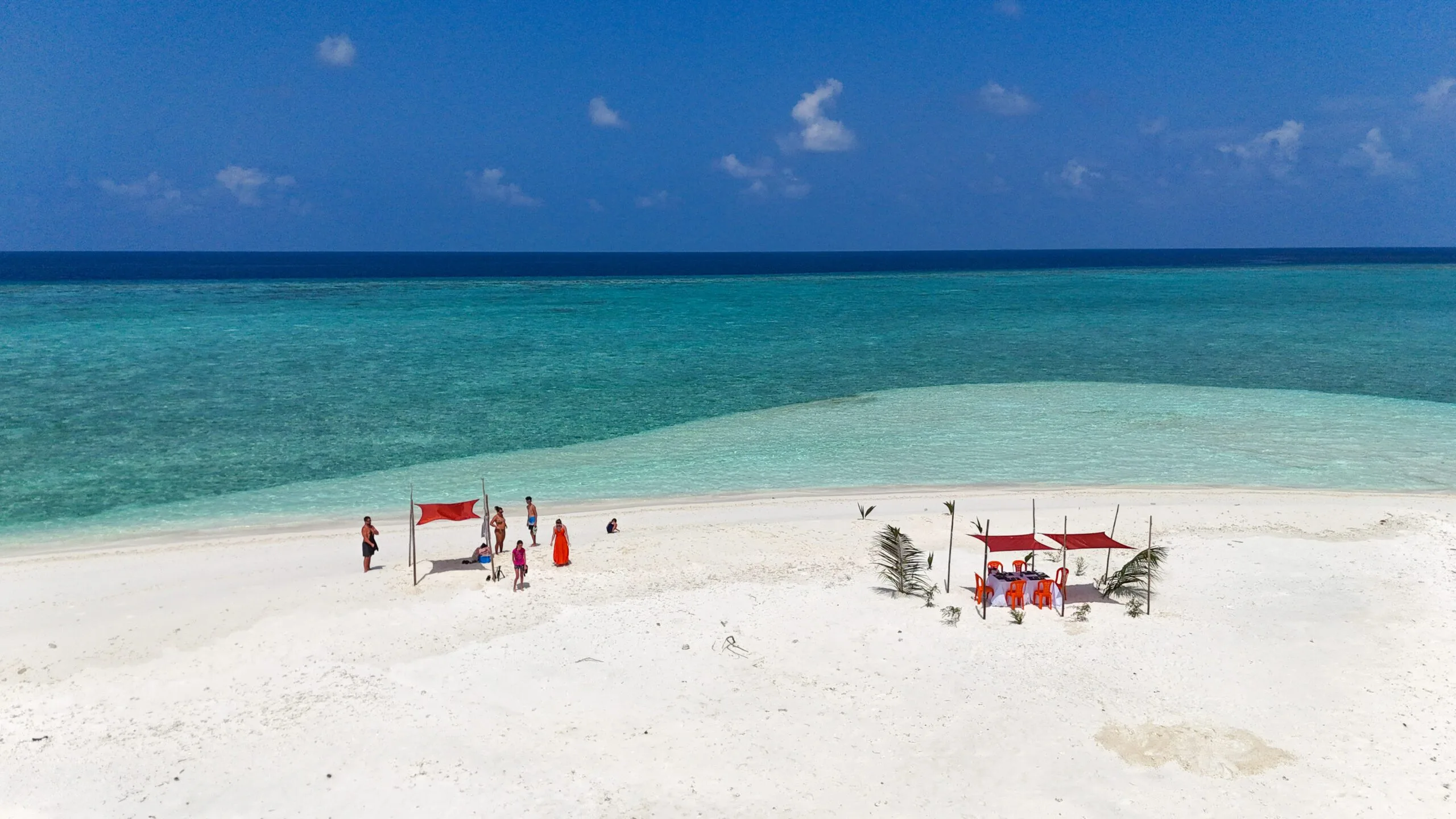 High-angle shot of excited guests picnicking on a sandbank, highlight of an Adventurous Holiday at Maldives