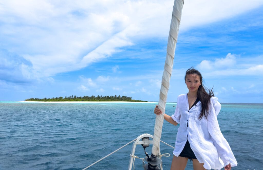 Adventurous woman capturing a selfie on a catamaran during her Maldives For Solo Travelers cruise past an uninhabited island
