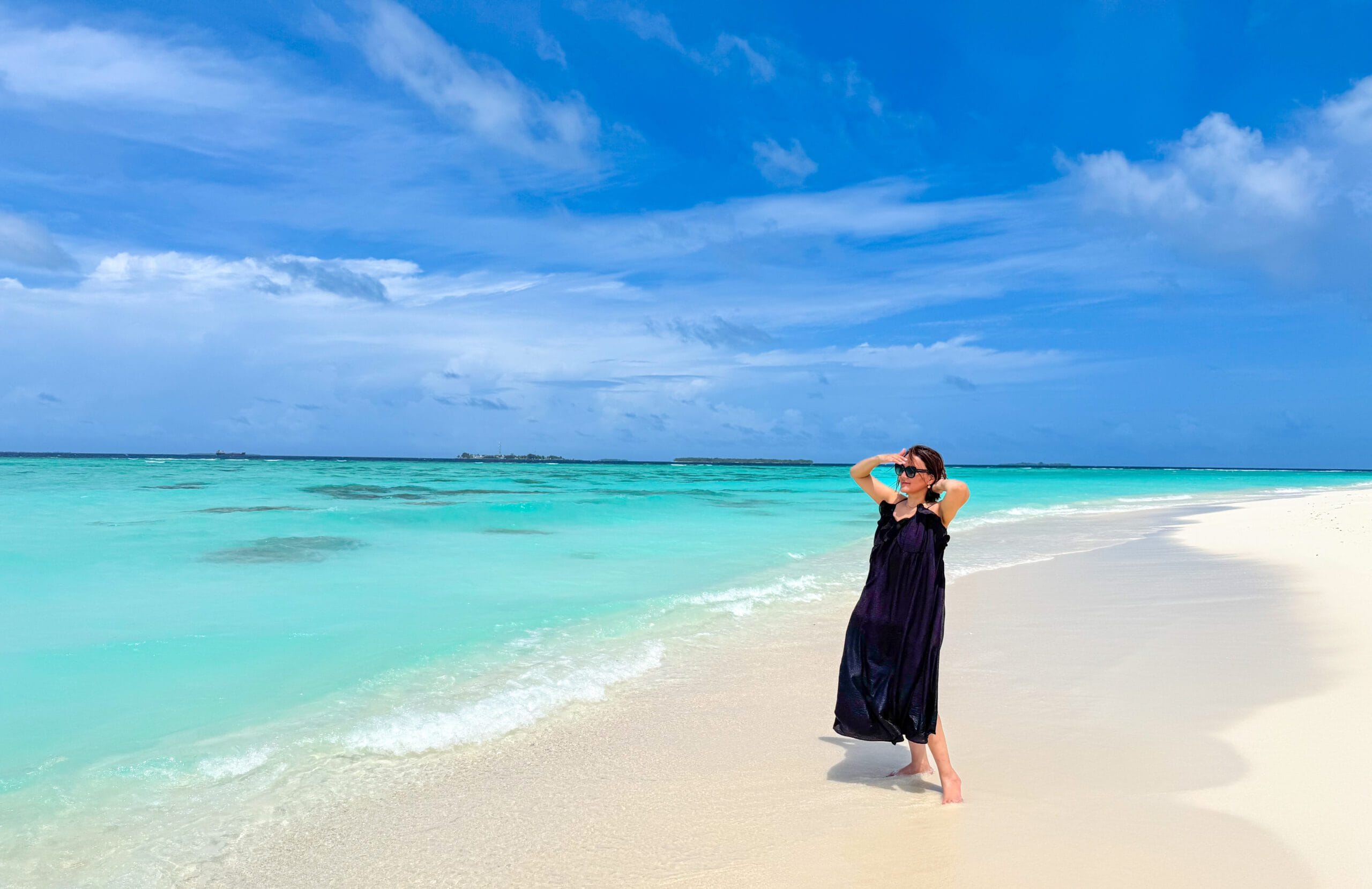 Solo traveler gazing at gentle waves on Fodhdhoo, enjoying her Maldives For Solo Travelers retreat