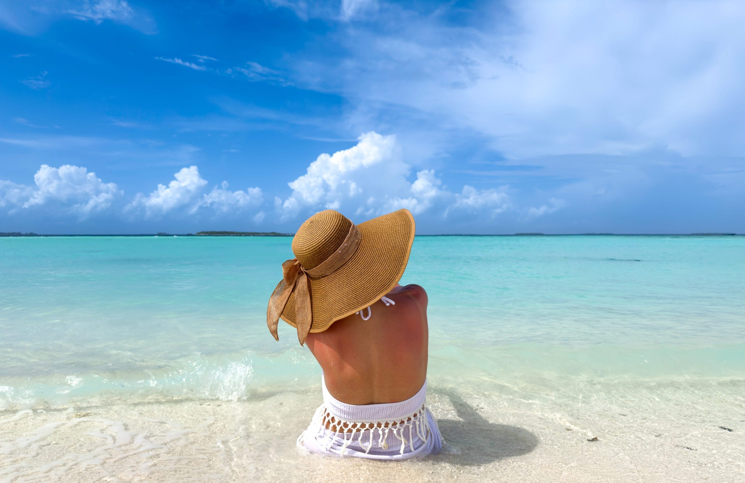 Peaceful woman seated by the beach, ocean horizon stretching across her Maldives For Solo Travelers escape